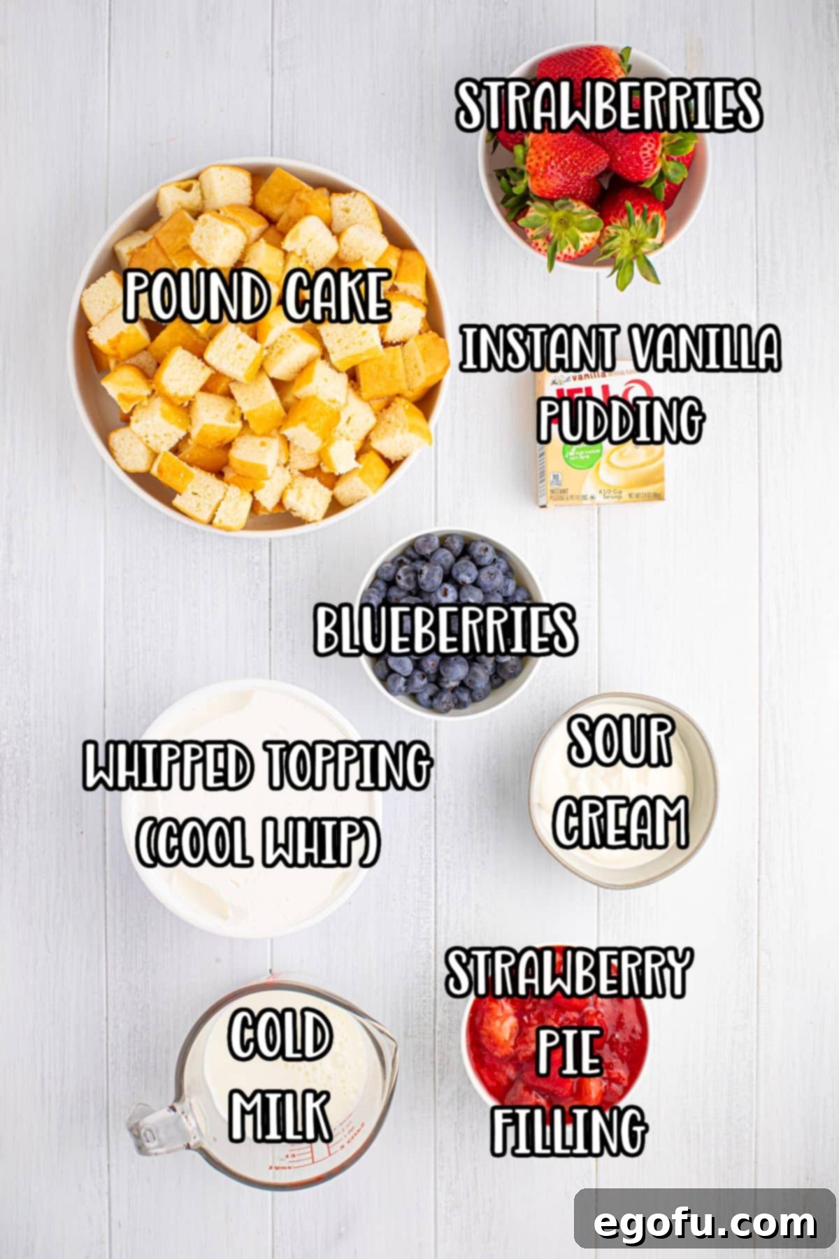 Ingredients laid out: Pound cake, fresh strawberries, fresh blueberries, sour cream, instant vanilla pudding mix, strawberry pie filling, whipped topping, and cold milk.