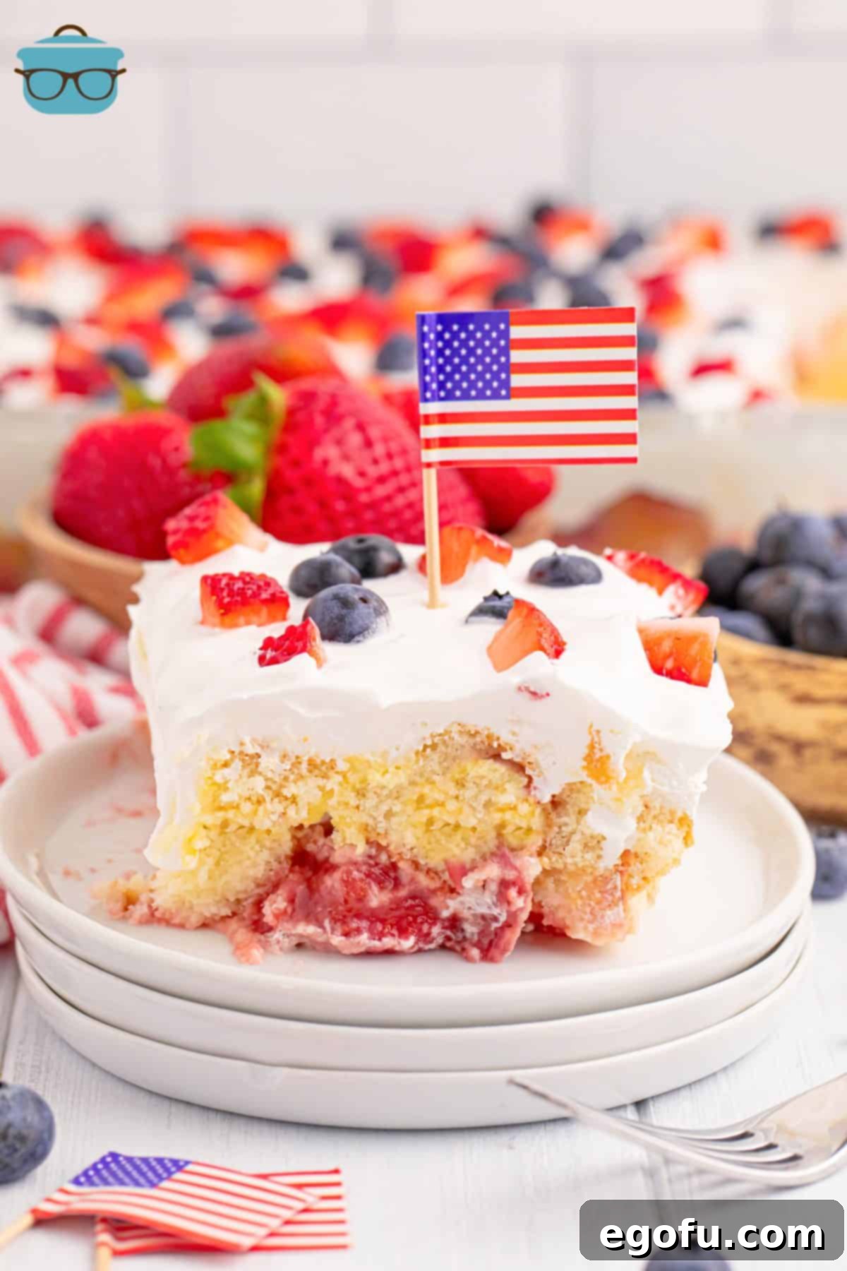 A slice of Patriotic Mixed Berry No Bake Dessert on a plate, adorned with a small American flag toothpick.