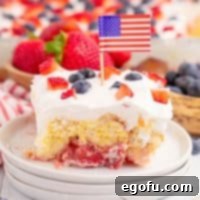 A dessert plate with a slice of Patriotic Mixed Berry Dessert, showcasing its distinct layers and berry topping.