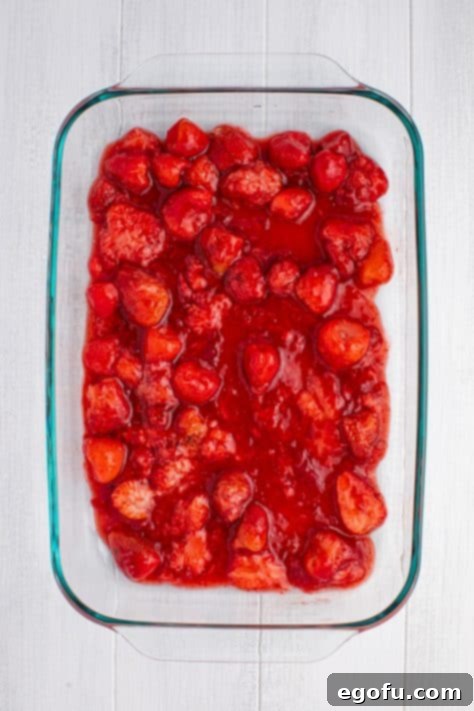 Strawberry pie filling spread out on a baking dish.