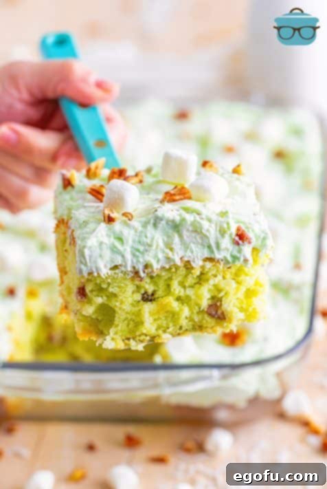 A serving utensil lifting a slice of Watergate Cake out of the dish.