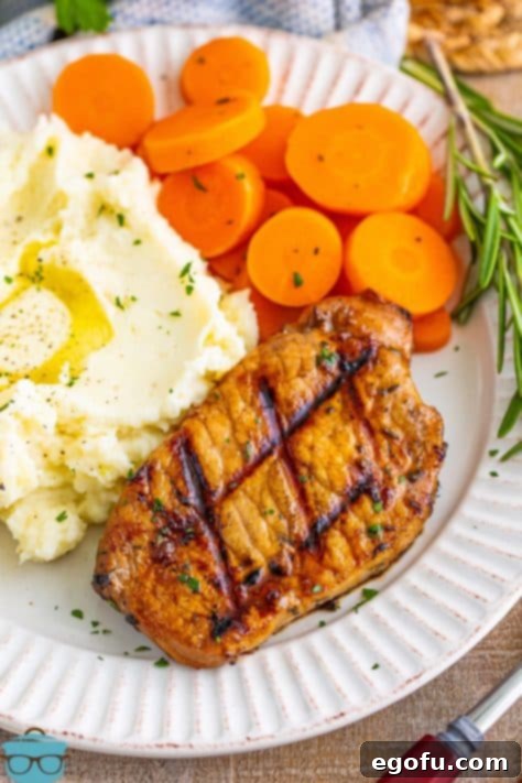 A vibrant plate featuring tender Grilled Balsamic Pork Chops, accompanied by fluffy mashed potatoes and bright, sliced carrots.