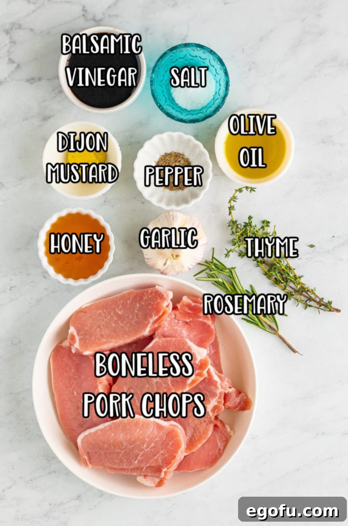 All the fresh ingredients laid out: boneless pork chops, thyme, rosemary, honey, dijon mustard, black pepper, garlic cloves, olive oil, salt, and balsamic vinegar.