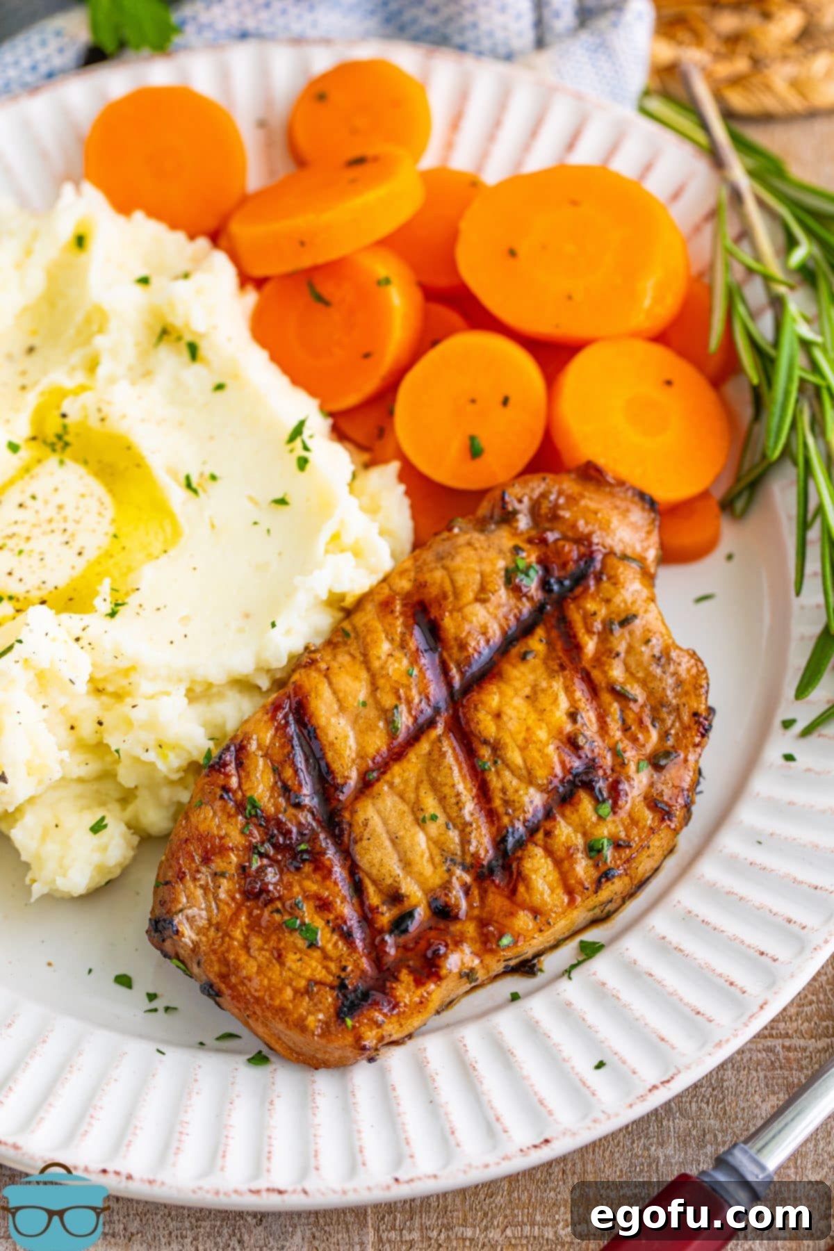 A beautifully presented plate of succulent Grilled Balsamic Pork Chops, accompanied by creamy mashed potatoes and vibrant sliced carrots.