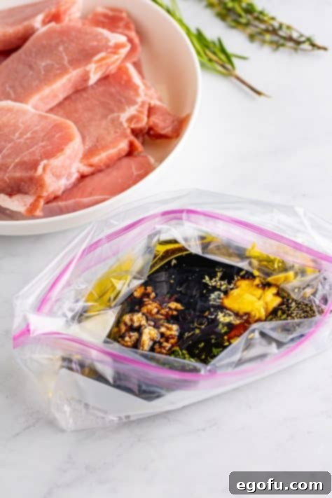 A Ziplock bag containing all the marinade ingredients: balsamic vinegar, olive oil, honey, minced garlic, dijon mustard, salt, chopped thyme, chopped rosemary and pepper.