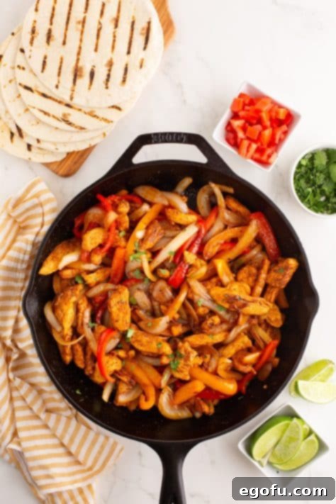 Chicken, onions, and bell peppers in a skillet.