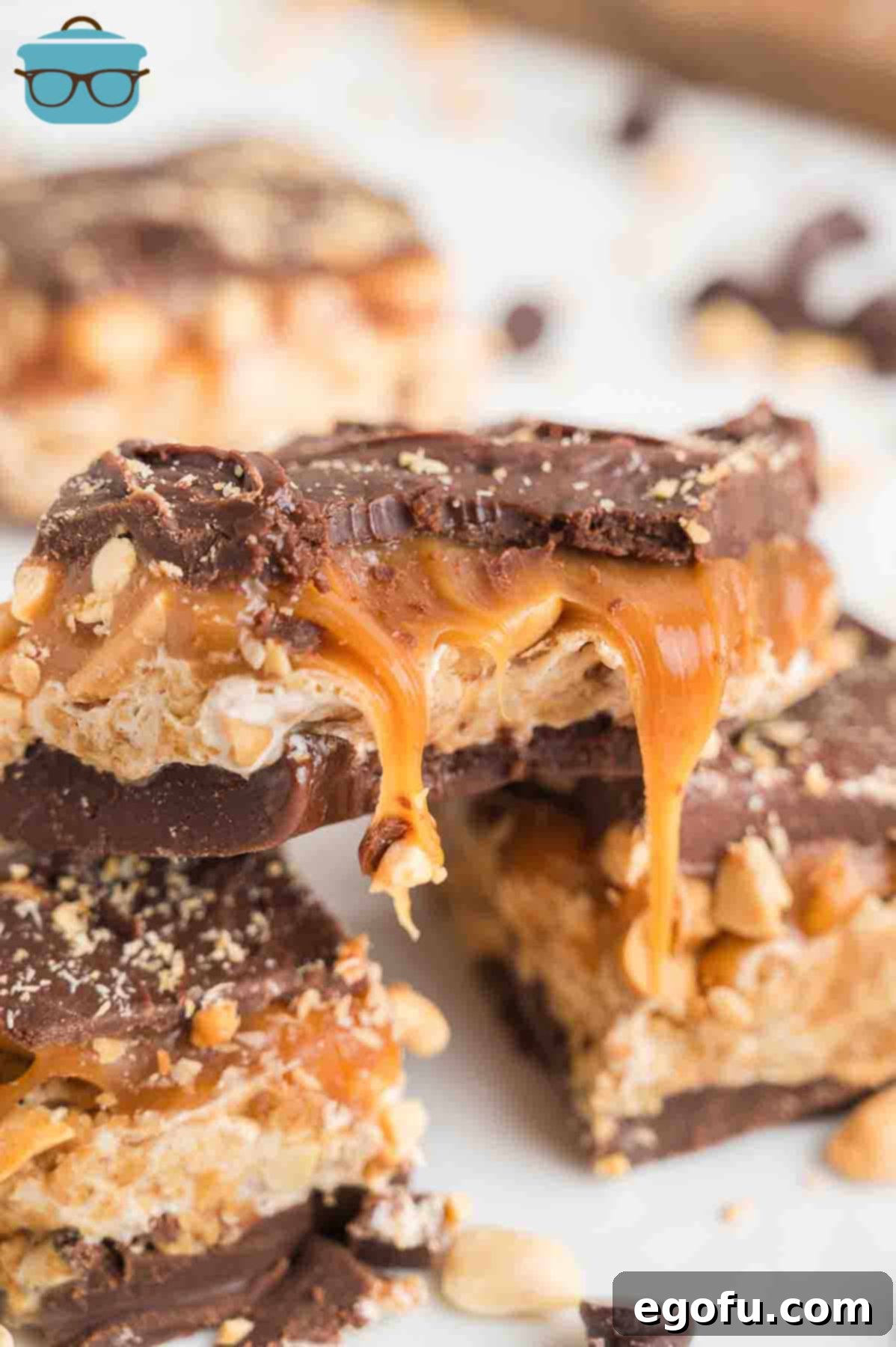 A pile of Snickers Bars with one missing a bite, showcasing the delicious layers of chocolate, caramel, and peanuts.