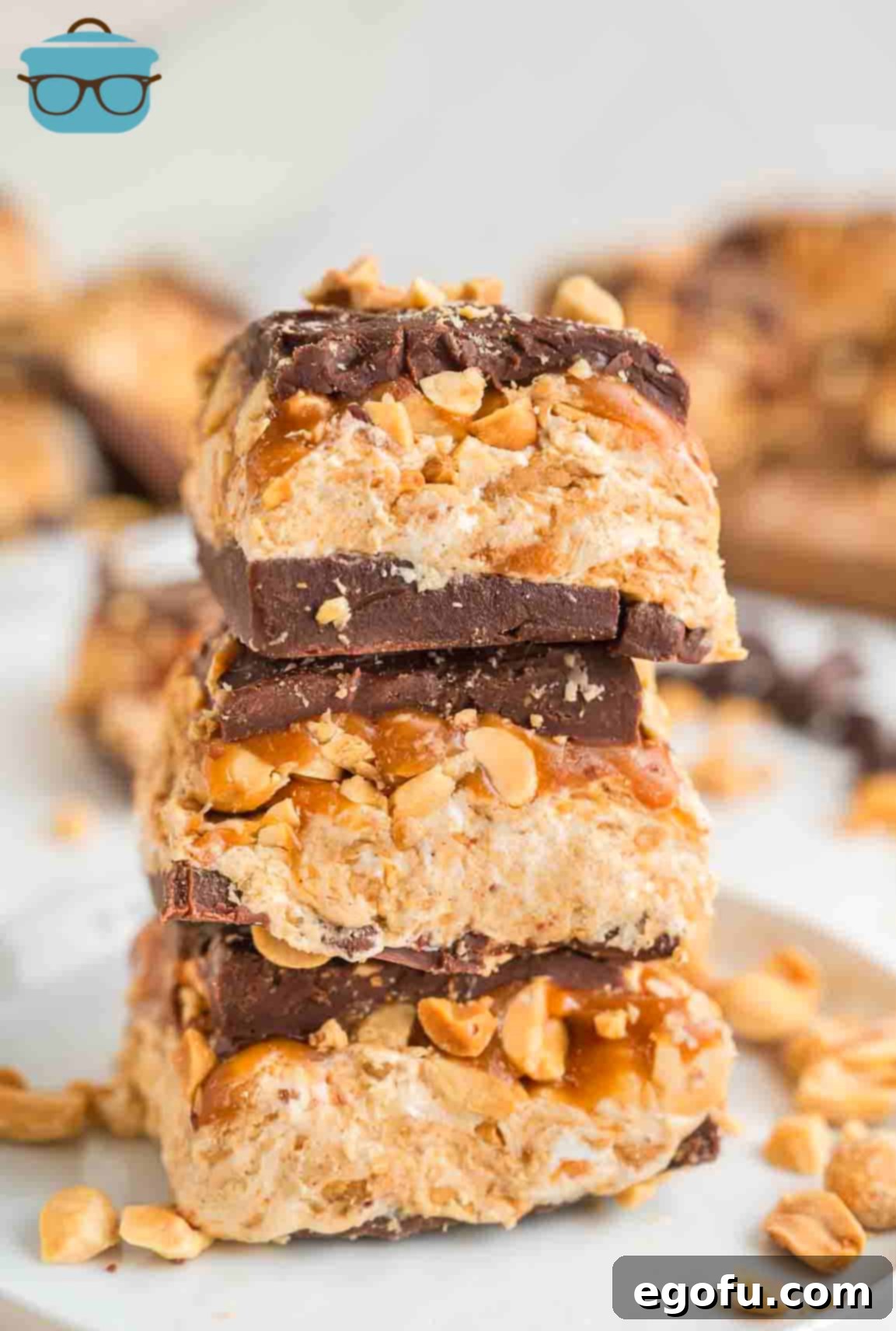 The final chocolate topping layer, with chopped peanuts sprinkled over it, completing the Snickers bars in the dish.