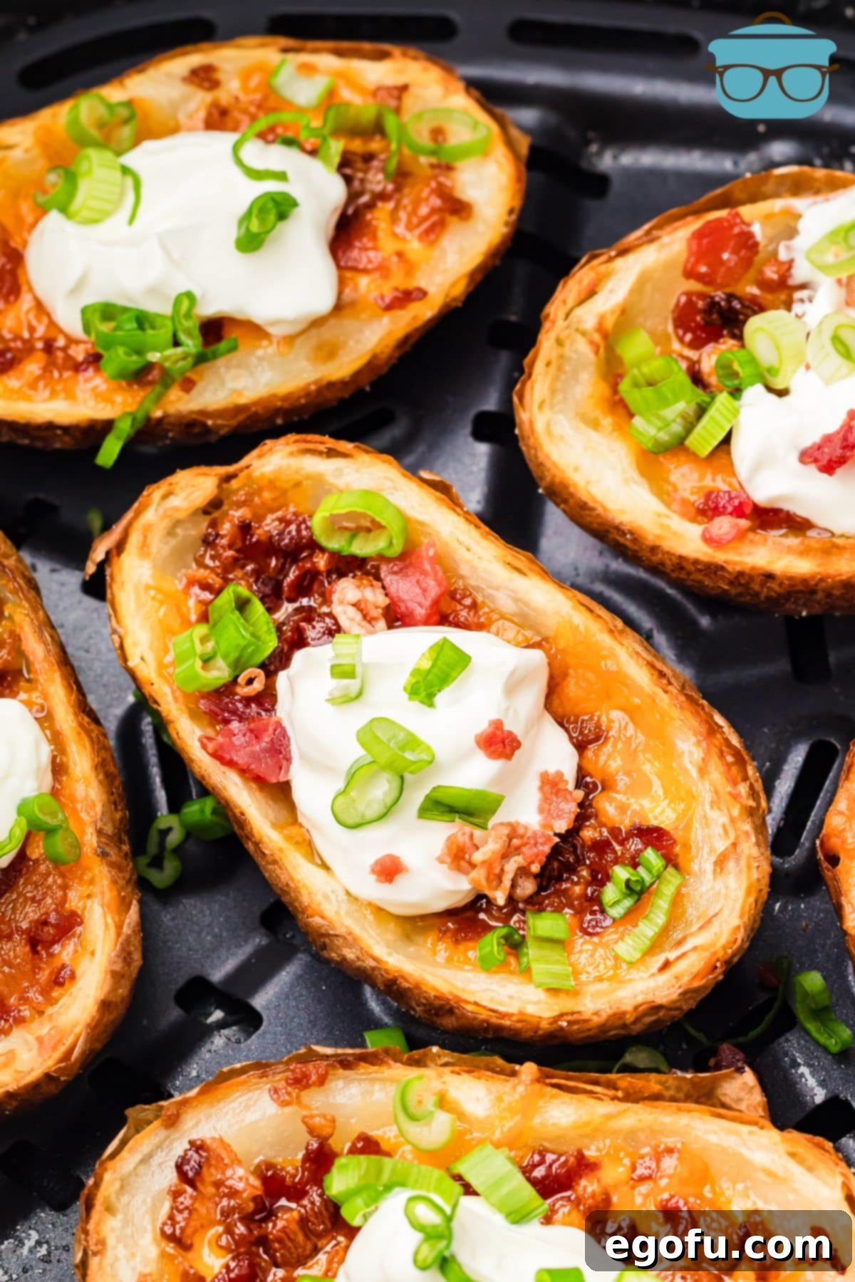 A serving of crispy Air Fryer Potato Skins garnished with melted cheese, bacon, and green onions, ready to be dipped.