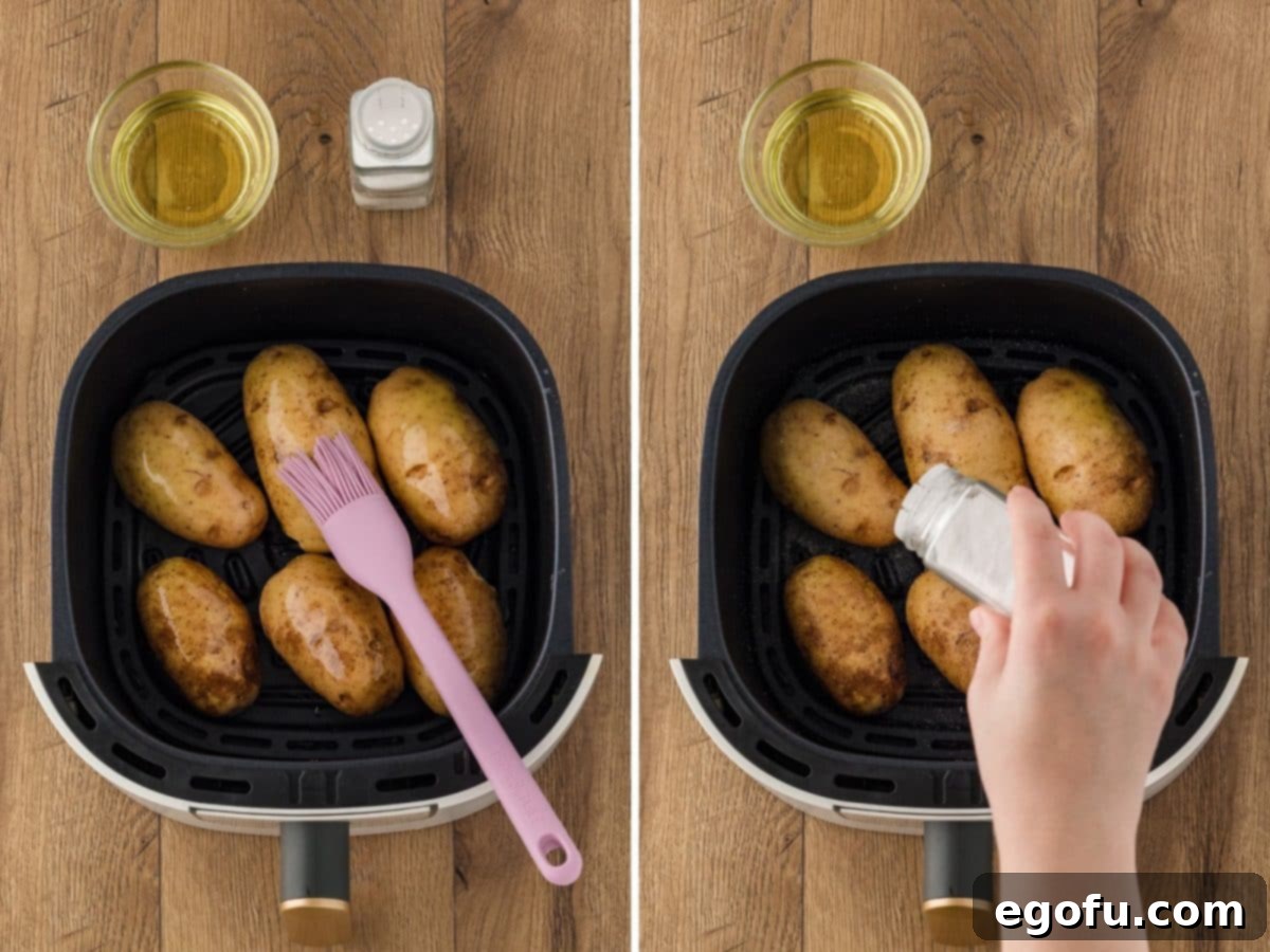 A hand is gently brushing olive oil onto Russet potatoes inside an air fryer basket, followed by sprinkling sea salt.