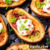 A close-up of a single Air Fryer Potato Skin, showing its crispy edge and cheesy filling.