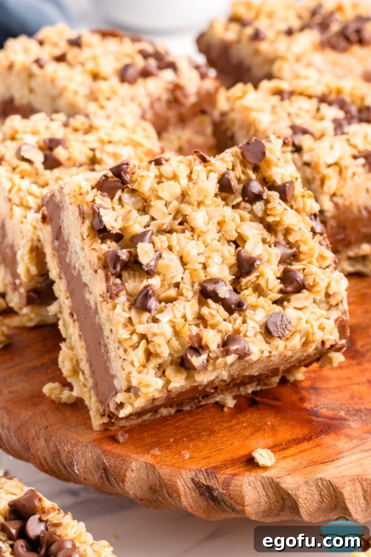 A stack of golden brown No Bake Chocolate Peanut Butter Oatmeal Bars with a rich chocolate and peanut butter layer in the middle, ready to be enjoyed.