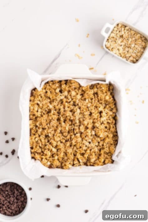 The remaining oat mixture being evenly sprinkled over the chocolate layer in the baking dish.