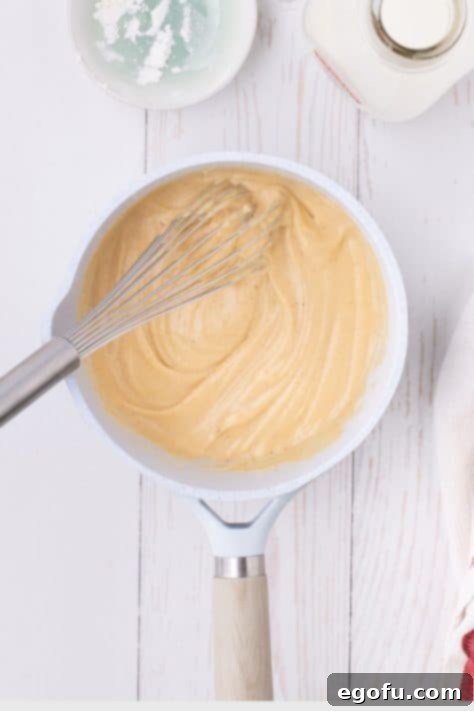 Golden Baked Chicken Ham and Swiss Casserole 17 A thick creamy sauce in a saucepan.