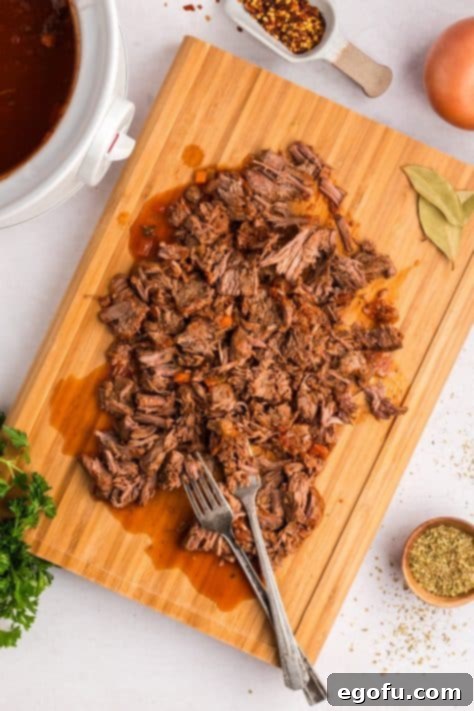Shredded beef chuck steak on a cutting board.