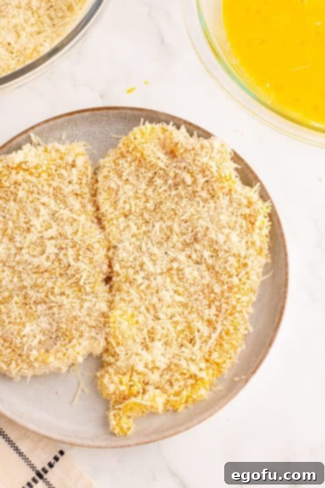 Crispy Parmesan Chicken Delight 11 A piece of chicken being coated in the Parmesan-panko breading mixture.