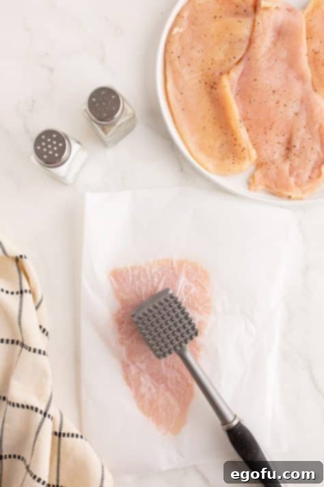 Crispy Parmesan Chicken Delight 9 A mallet beating a piece of chicken breast.