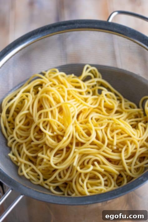 Spaghetti noodles in a strainer, drained and ready.