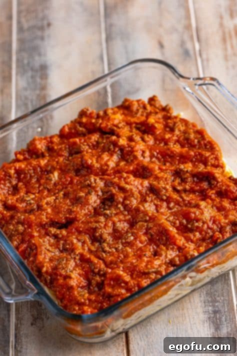 Meat sauce spread over the spaghetti layer in the baking dish.
