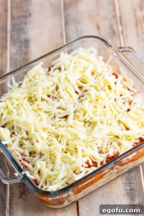 Shredded mozzarella cheese generously sprinkled over the meat sauce layer.