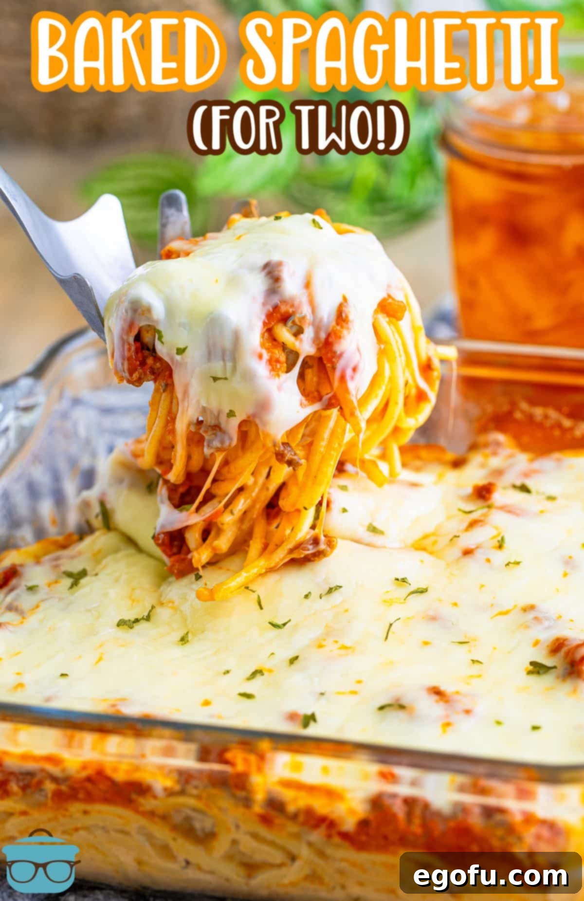 A baking dish filled with Baked Spaghetti for Two, with a serving utensil ready to scoop.
