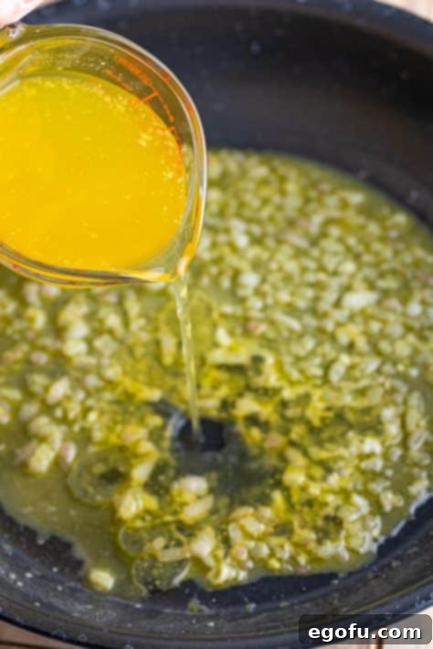 Zesty Piccata Chicken Bites 20 Chicken broth being added to the shallot mixture in a skillet.