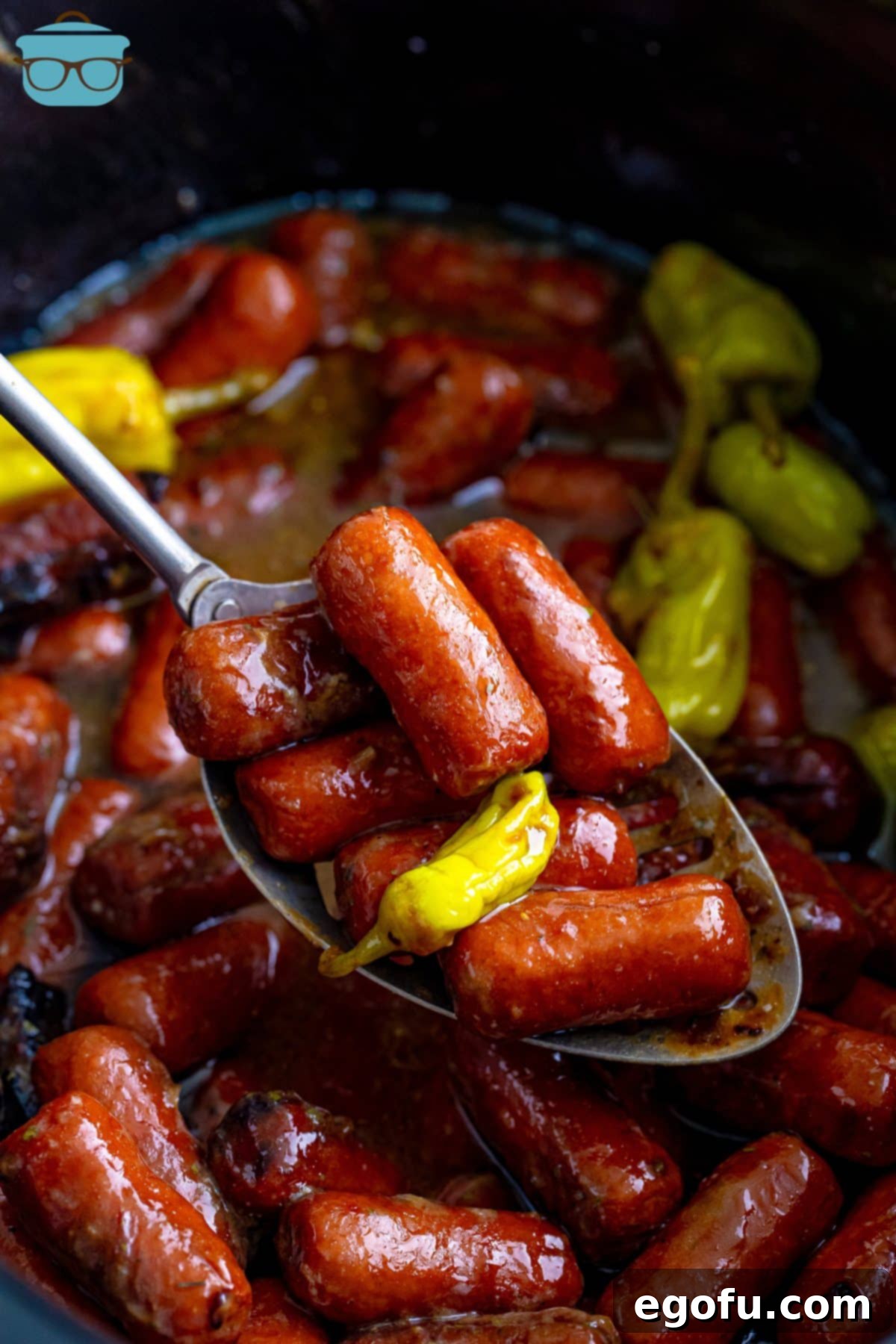 Irresistible Slow Cooker Mississippi Sausages 7 A serving utensil holding a generous portion of Crock Pot Mississippi Lit'l Smokies, glistening with sauce, ready for serving.