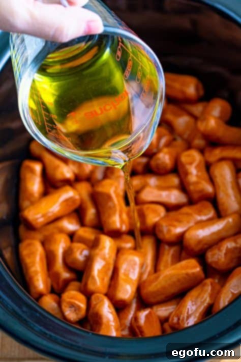 Irresistible Slow Cooker Mississippi Sausages 10 Peperoncini juice being poured in a slow cooker.