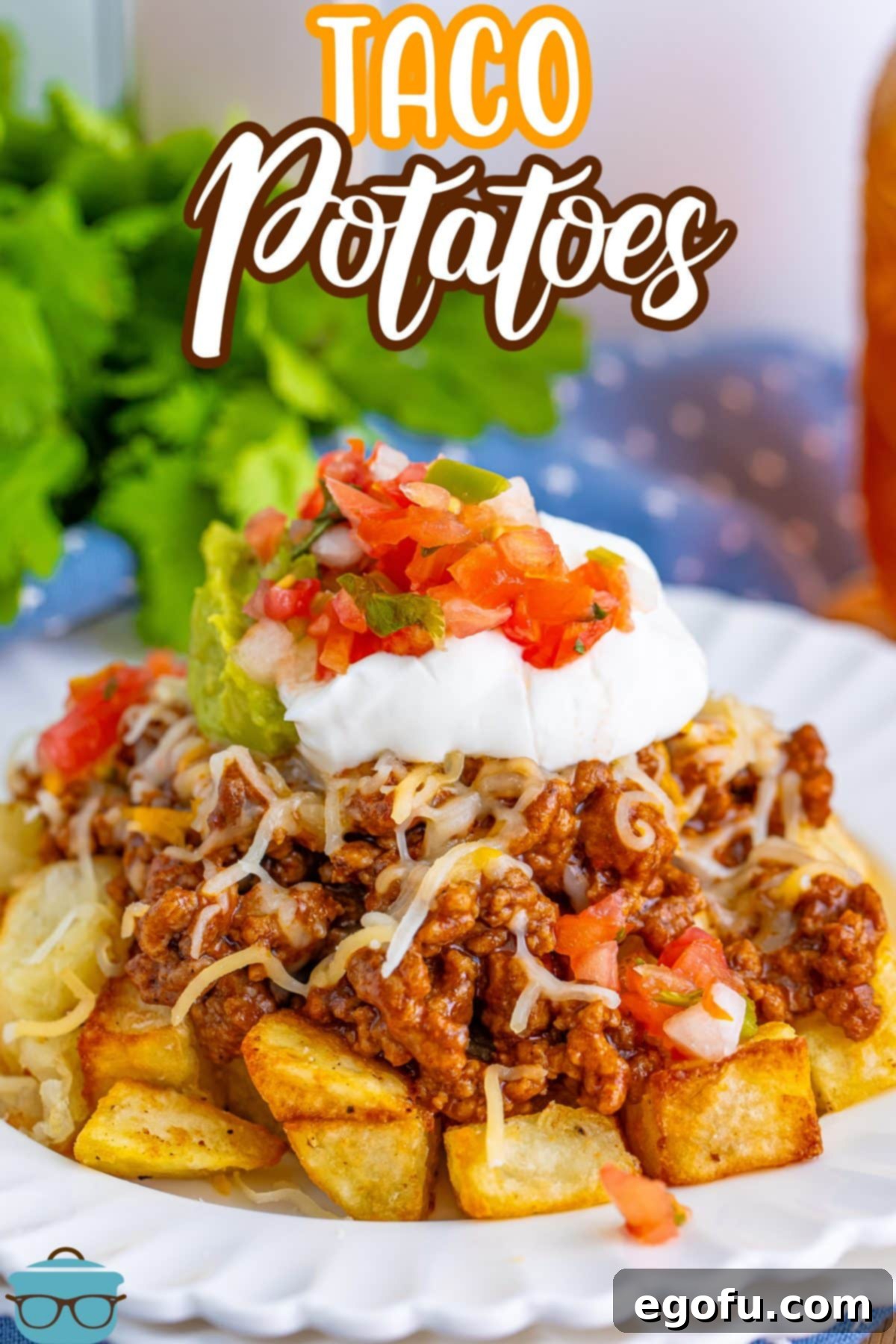 A vibrant pile of Taco Potatoes generously topped with cheese and fresh ingredients on a white plate.