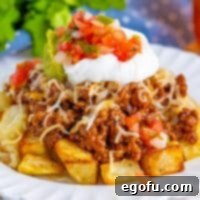 Close up looking at a large pile of Taco Potatoes, garnished with fresh cilantro and sour cream.