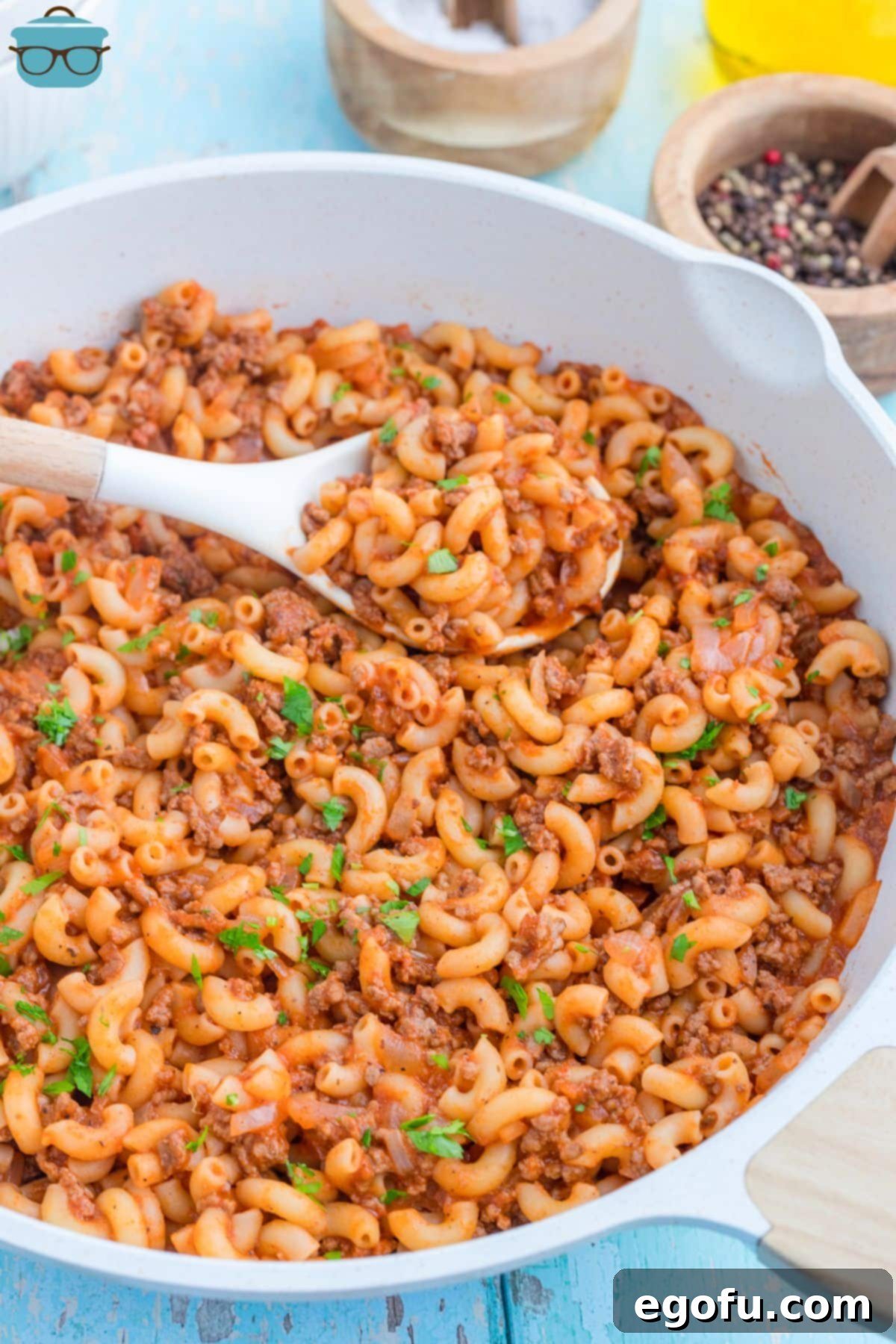 A wooden spoon in a skillet of Beefaroni.