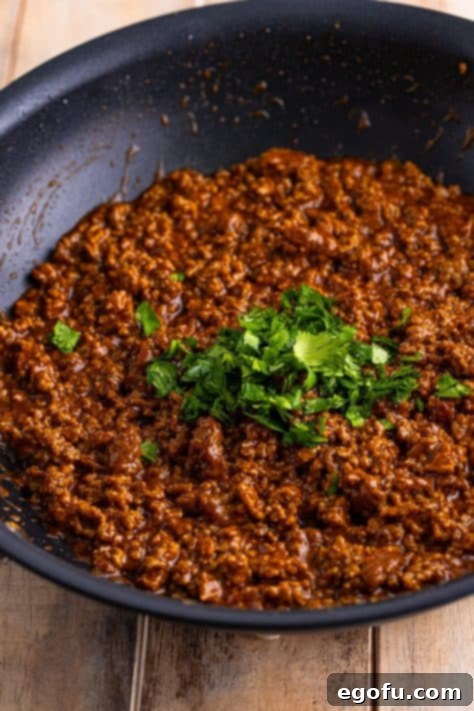 Ground beef and cilantro in a pan.