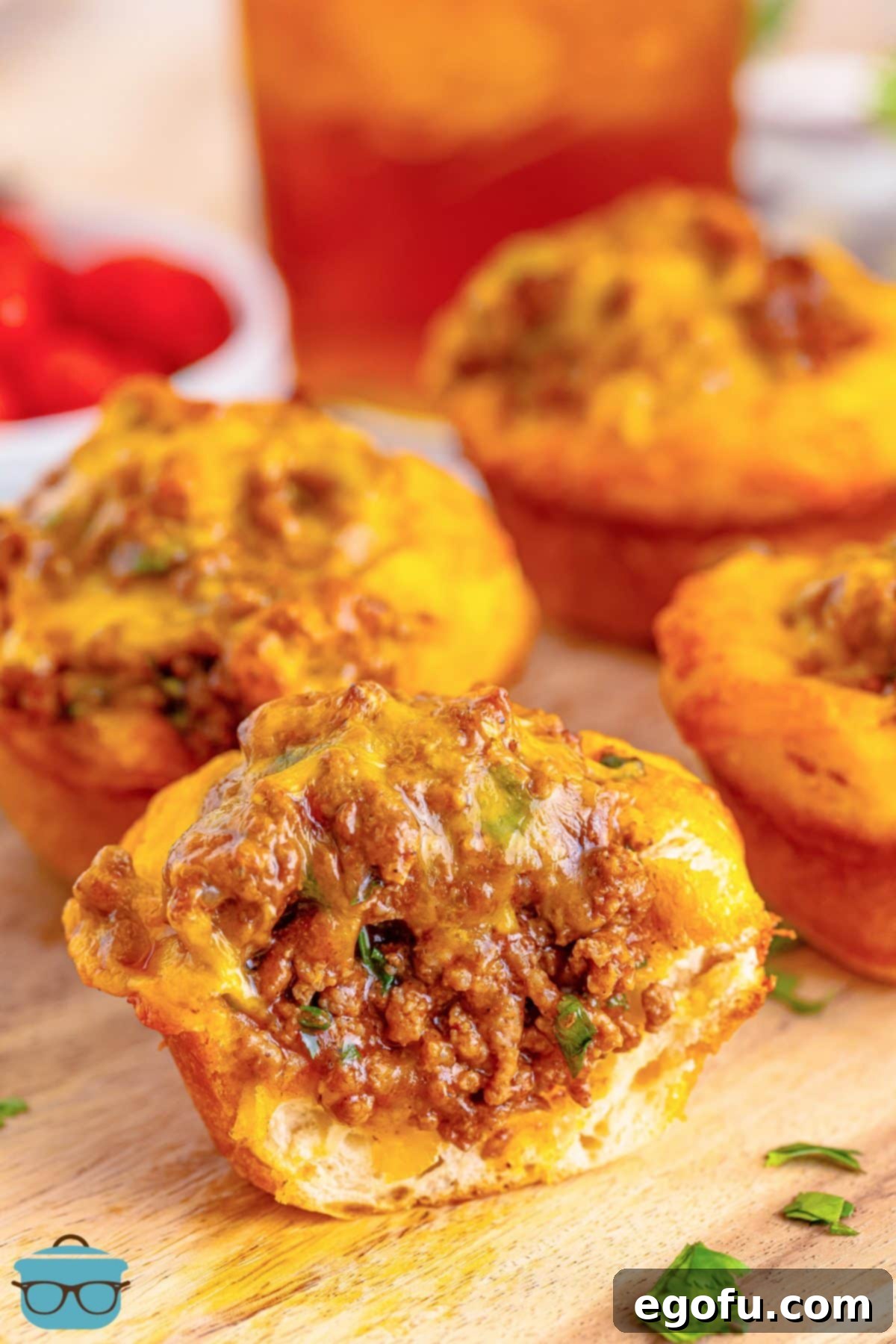 Close-up view of a few golden brown Taco Biscuit Cups fresh from the oven, one cut in half to reveal the gooey cheese and savory filling.