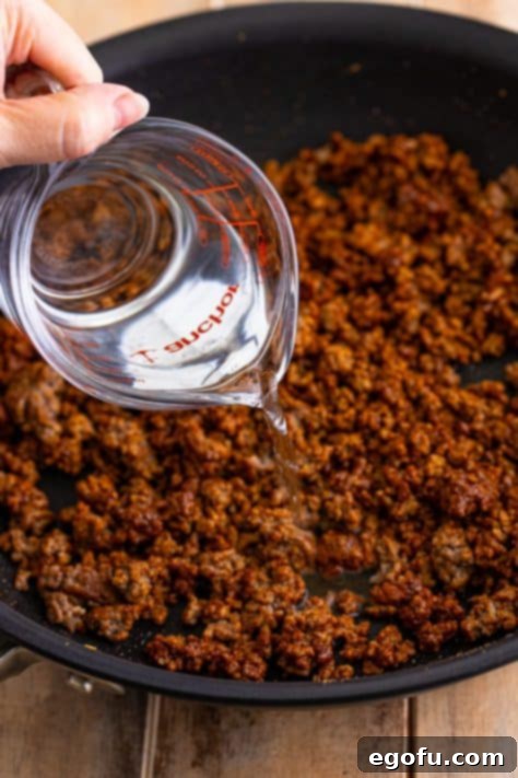 Water being poured on ground beef.
