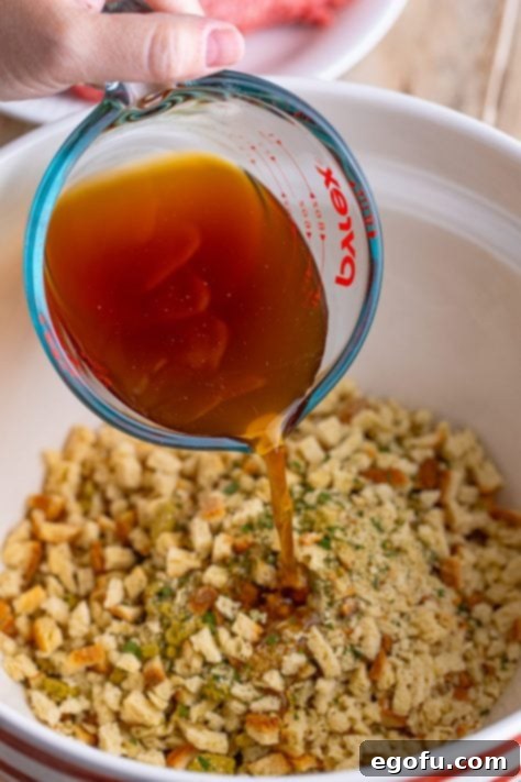 Beef broth being added to dry stuffing mix in a large mixing bowl, beginning the rehydration process for the meatloaf base.
