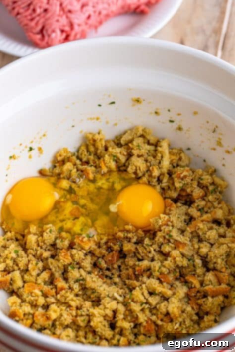 Fresh eggs and Worcestershire sauce being poured into the moistened stuffing mix, ready to be stirred into the meatloaf base.