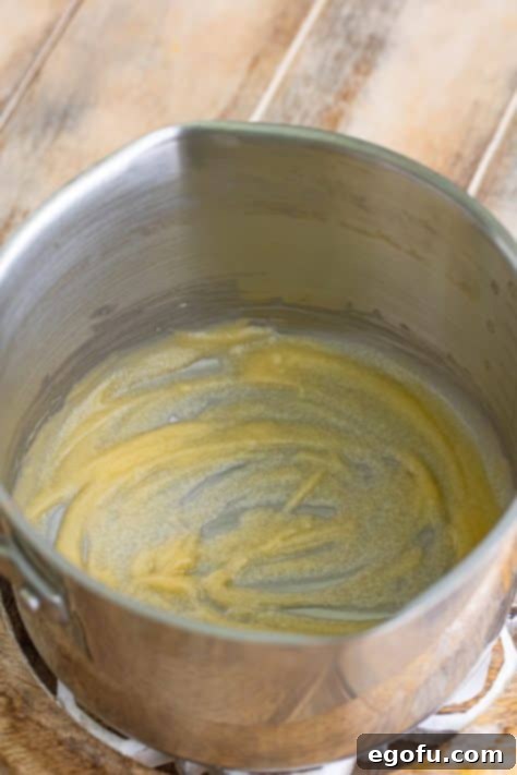 Melted butter combined with flour in a saucepan, forming a smooth roux, the foundational step for a rich gravy.