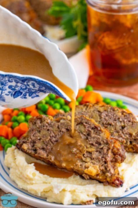 Rich, brown gravy being artfully poured from a gravy boat over a freshly sliced portion of Stove Top Stuffing Meatloaf, highlighting its irresistible appeal.