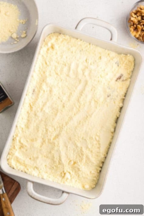 Cake mix on top of peach pie filling in a dish.