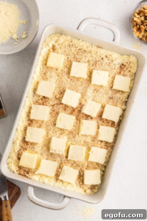 Slabs of butter on cake mix on peach pie filling in a dish.