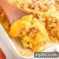 Looking down on a wooden spoon getting a scoop of Peach Dump Cake.