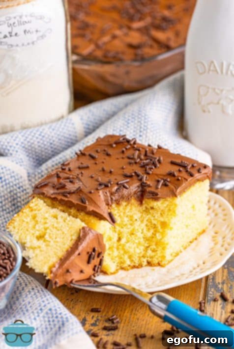 A slice of yellow cake with chocolate frosting on a plate with a fork holding a bite.
