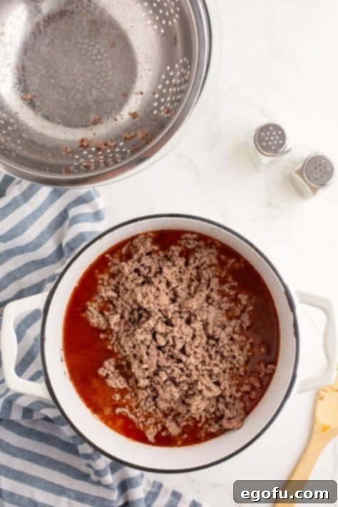 Cincinnati's Signature Chili 14 Cooked ground beef being added to a pot of chili.