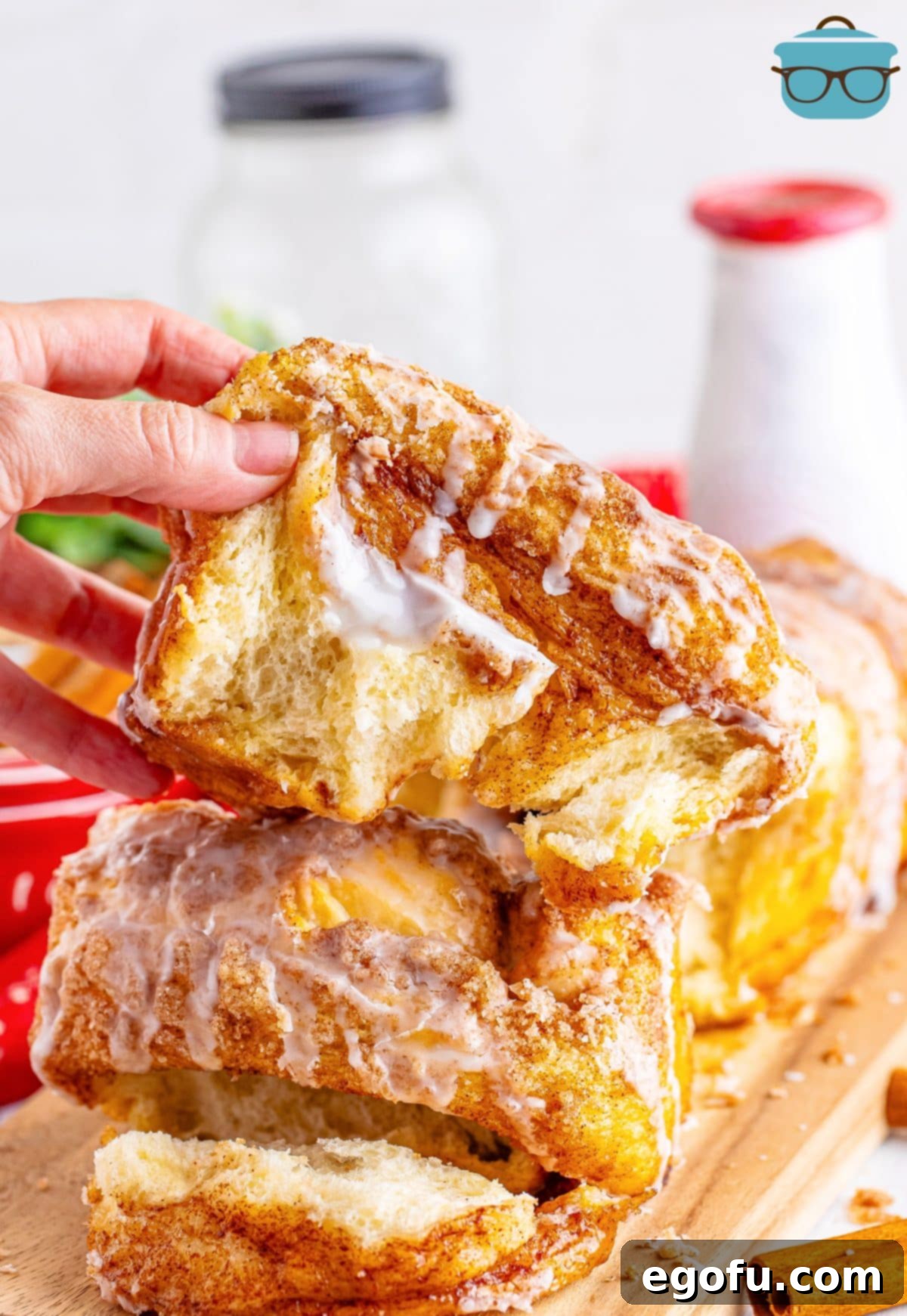 A hand picking up a slice of gooey Dollywood Cinnamon Bread, freshly baked and glazed.