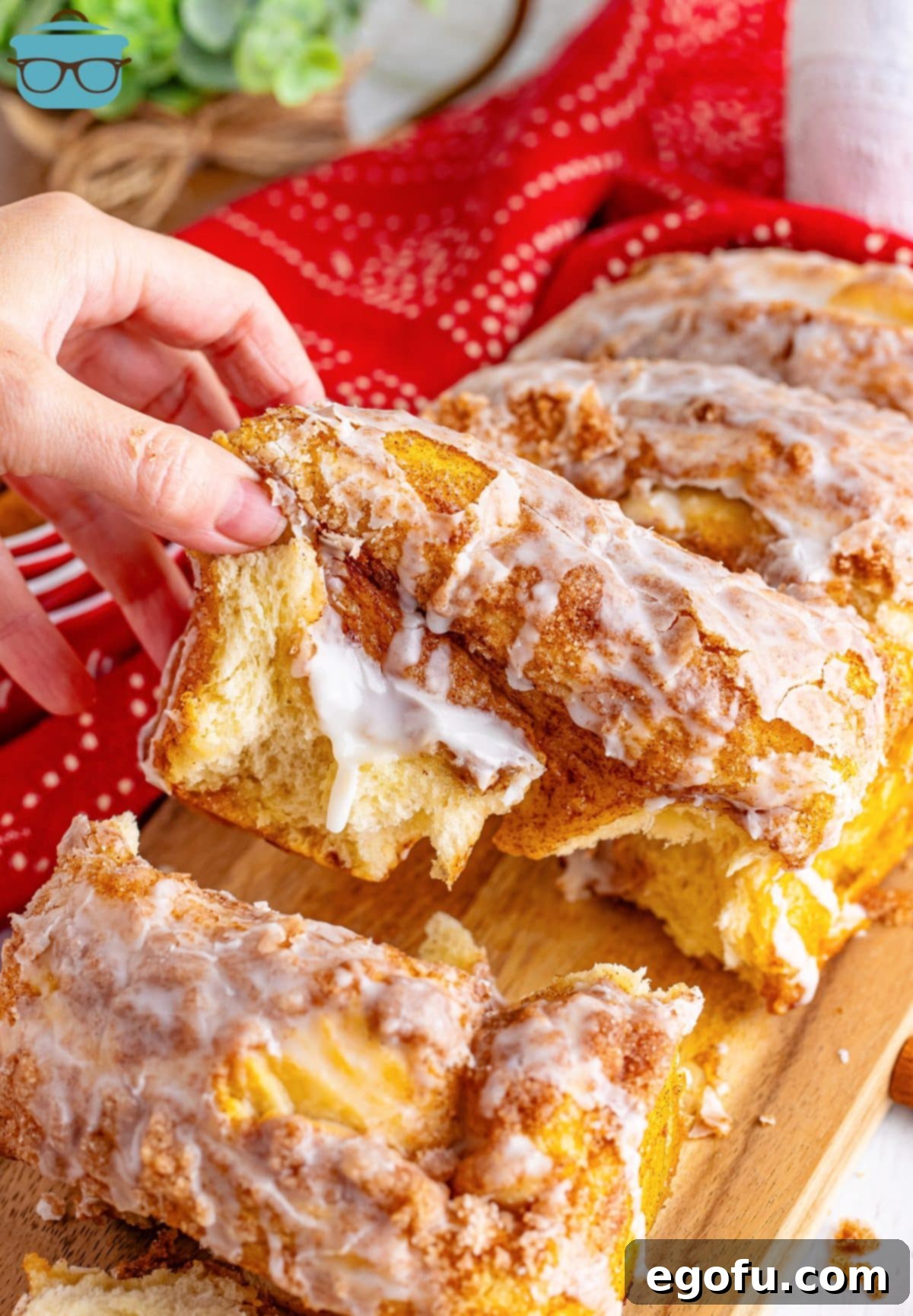 A hand reaching for a slice of sweet, warm Dollywood Cinnamon Bread, ready to be enjoyed.