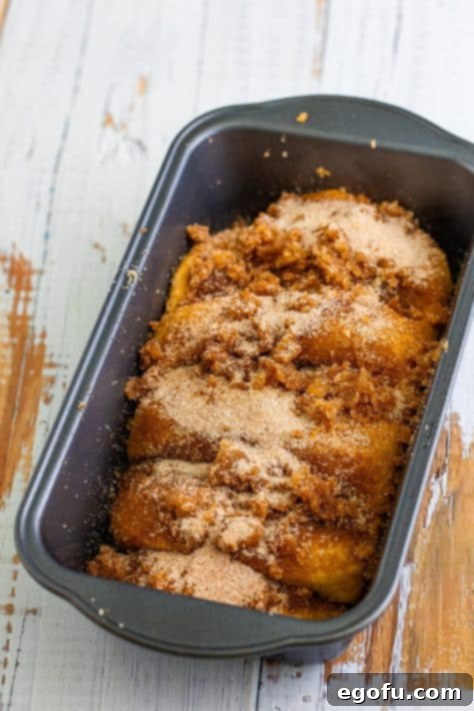 A raw loaf of cinnamon bread in a baking pan.