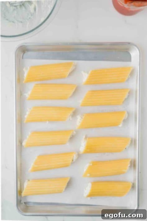 Effortless Manicotti 12 Cheese mixture filled manicotti shells on a lined sheet.
