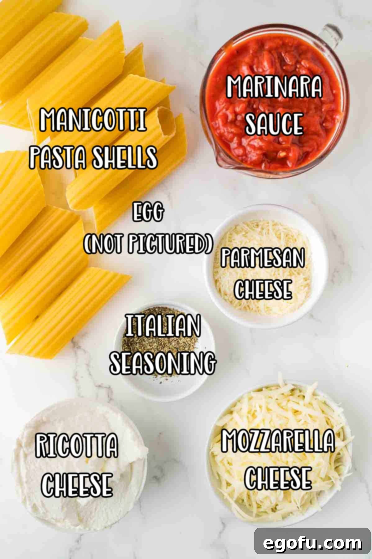 Effortless Manicotti 4 A flat lay of all the essential ingredients for Manicotti: uncooked pasta shells, a jar of marinara sauce, a tub of ricotta cheese, an egg, bowls of mozzarella and Parmesan, and small bowls of Italian seasoning and garlic powder.