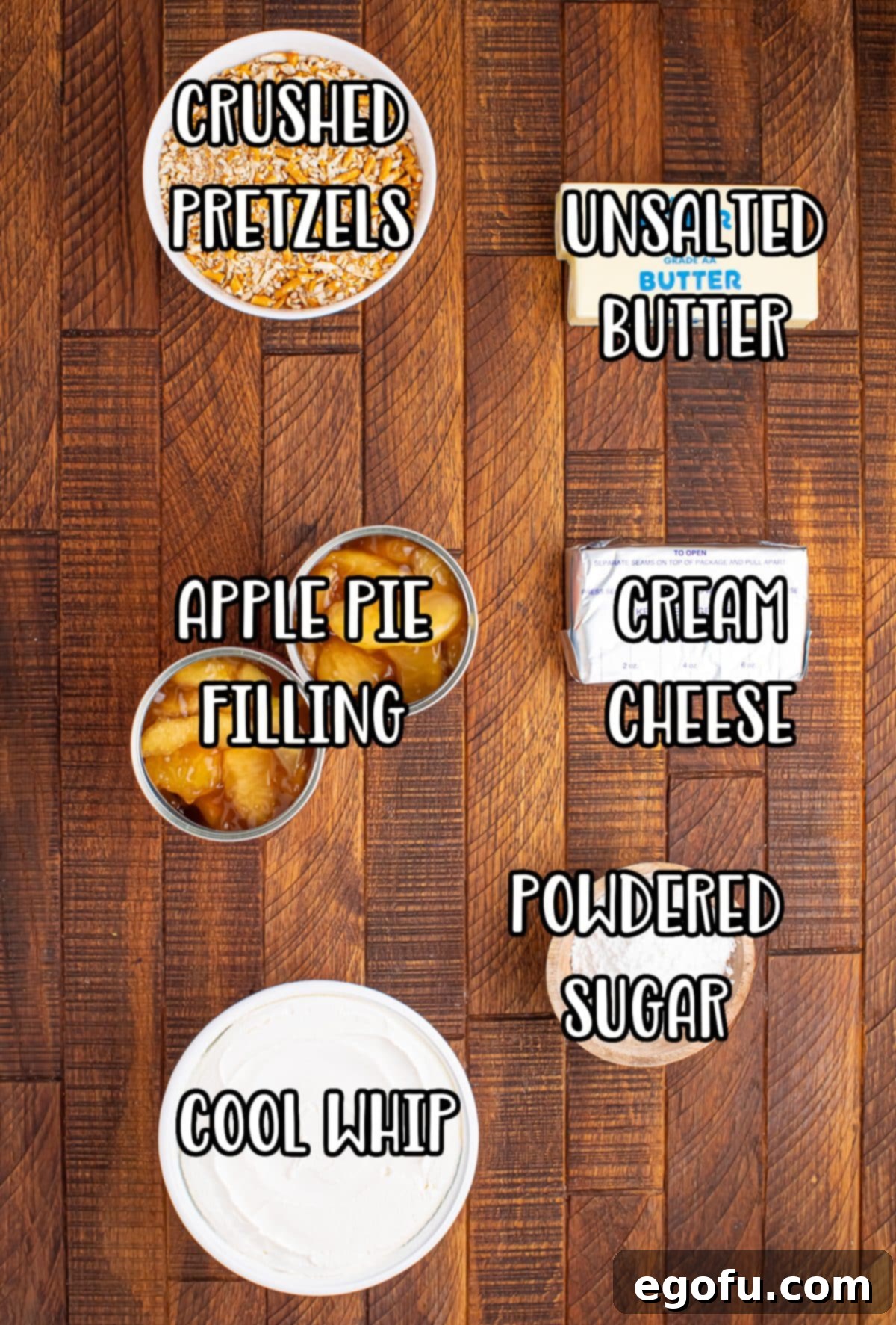 A visual display of all the ingredients needed for Apple Pretzel Salad: pretzels, butter, cream cheese, powdered sugar, whipped topping, and apple pie filling.