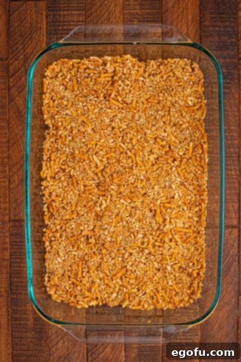 Crushed pretzels mixed with melted butter in the bottom of a baking dish.